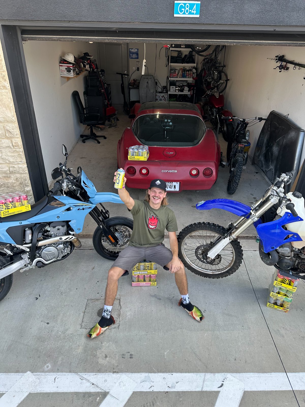 Joe in his garage with C4 cases, dirt bikes, and a Corvette